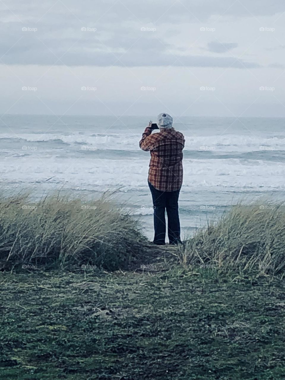 Woman on the beach taking a photo of the ocean 