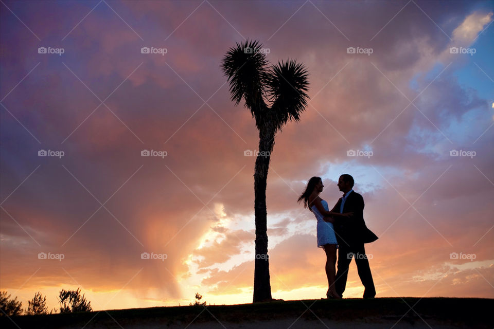 Young lovers under the heart shaped joshua tree, on a summer sunset