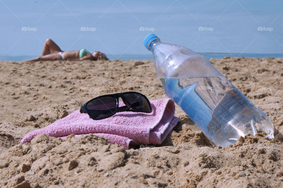 Bottle with clean drinking water lies on the beach