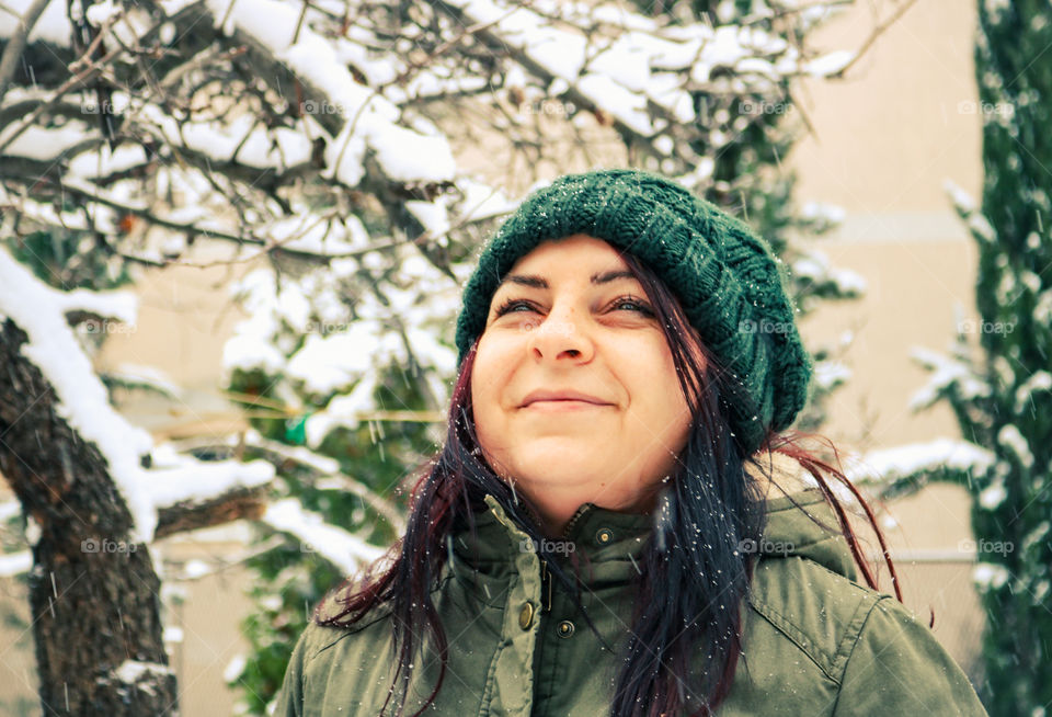 Woman with knit hat outdoors in the garden while snowing