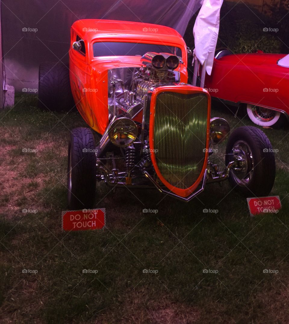 Reddish-orange Ford with a modified engine at a car show