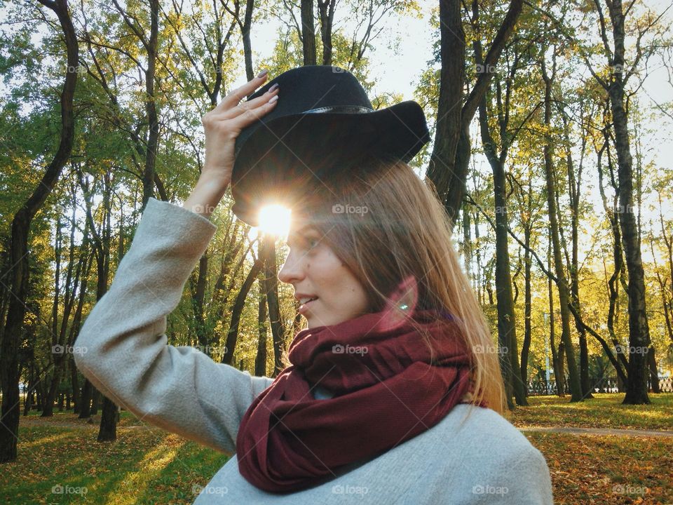 Close-up of a young woman standing with hat