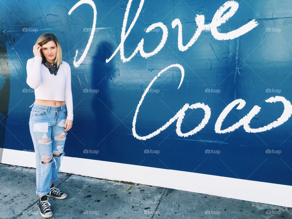Young woman standing in front of wall with I love cow text