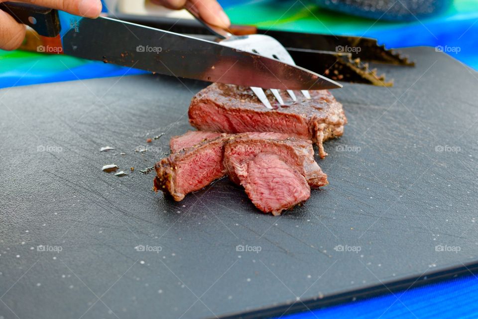 A steak grilled steak being sliced with a knife and fork