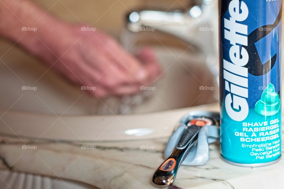 A man prepares to shave himself by wetting his hands