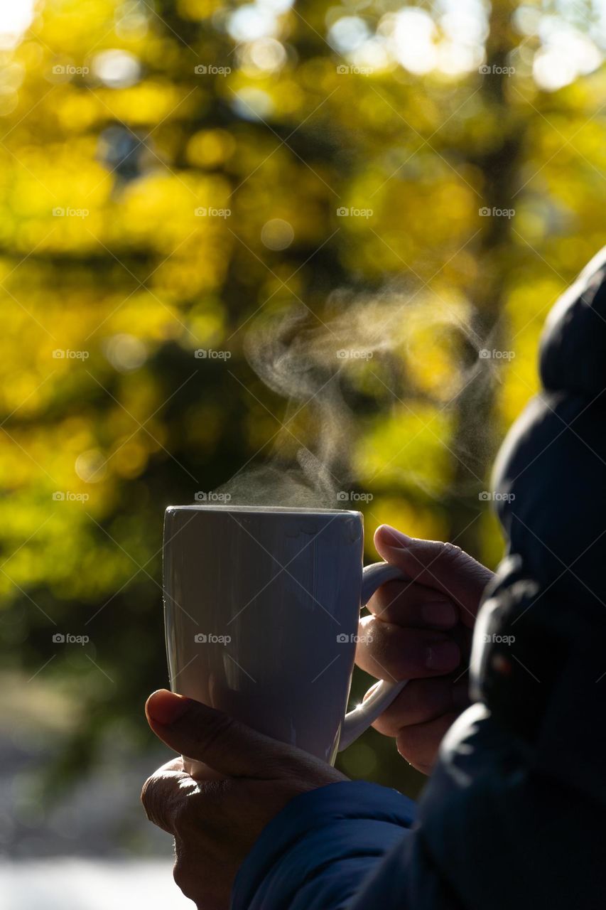 Drinking hot coffee with fall colors in the background 