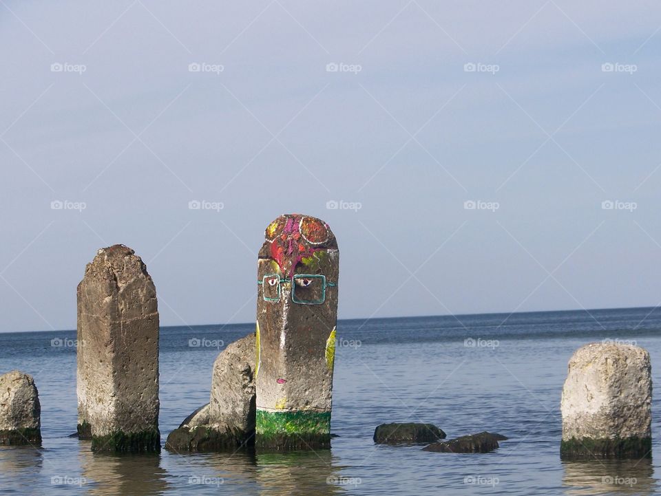 Painted stone in the sea. Face on a stone. Artwork. 