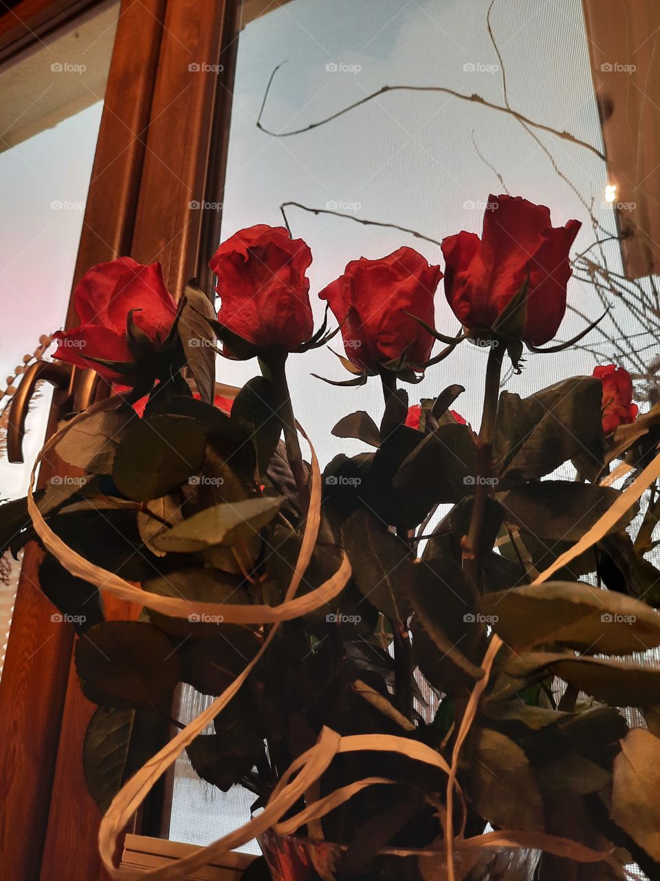 bouquet of red roses on a windowsill  illuminated by artificial light