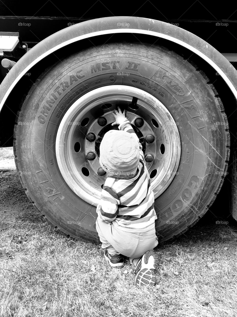 Small child fascinated by a big wheel.