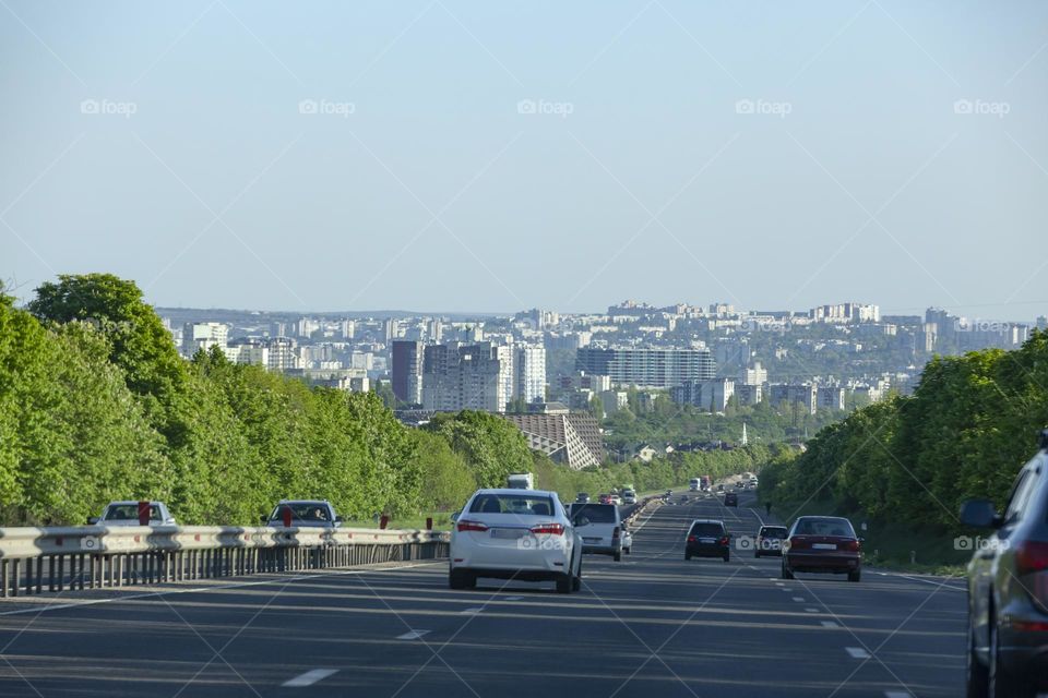 Vehicles and traffic. Less cars means less traffic. Multi-lane highway against the backdrop of a green city.