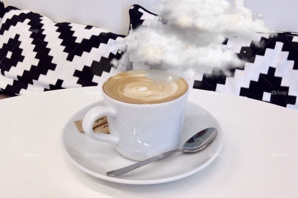 Cup of coffee on white table, clouds