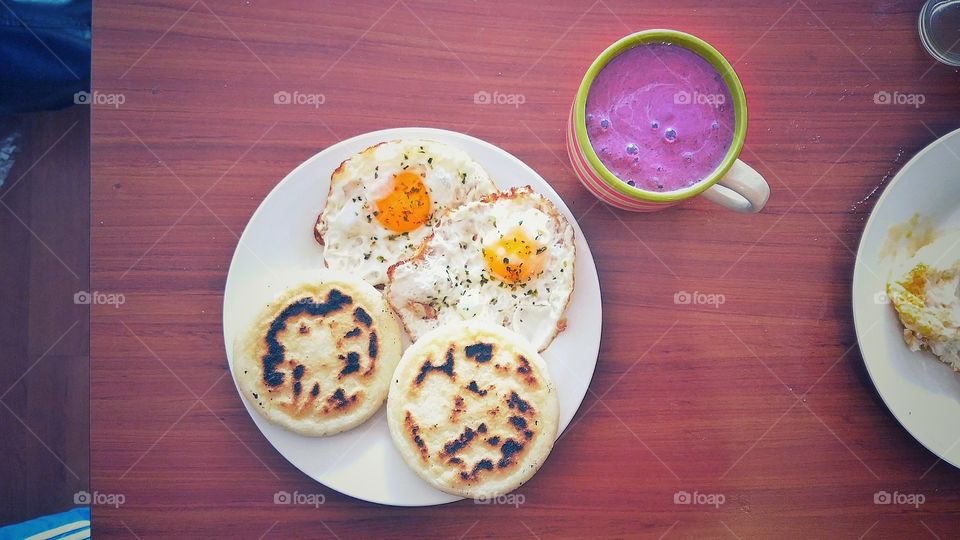 Arepas with friend eggs and berries smoothie