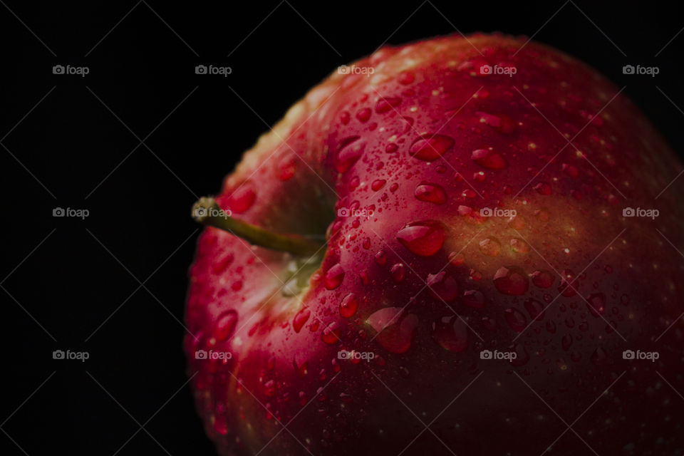 macro shot of red juicy apple covered with water drops