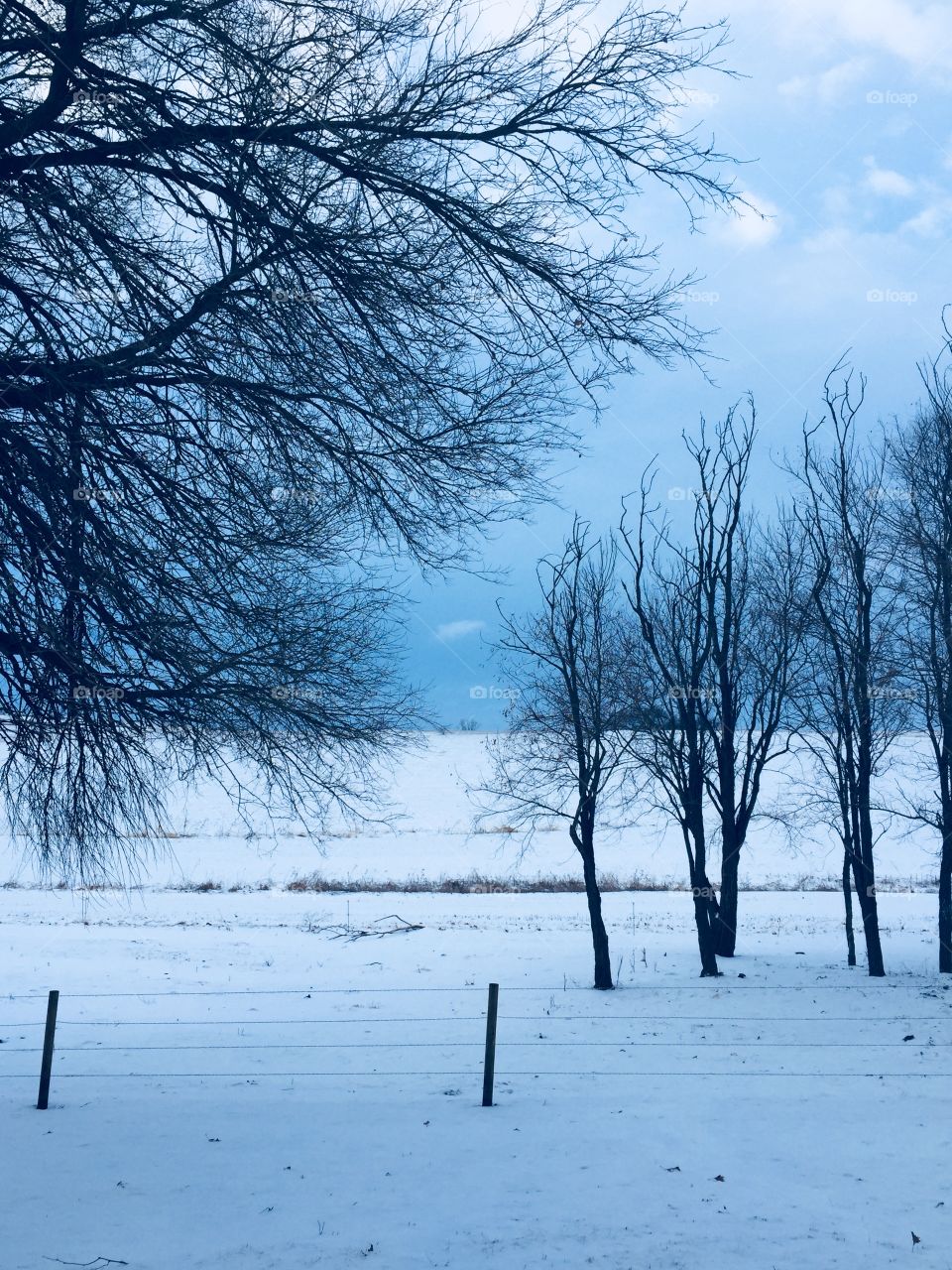 A wintery rural landscape against the dark sky of an approaching storm