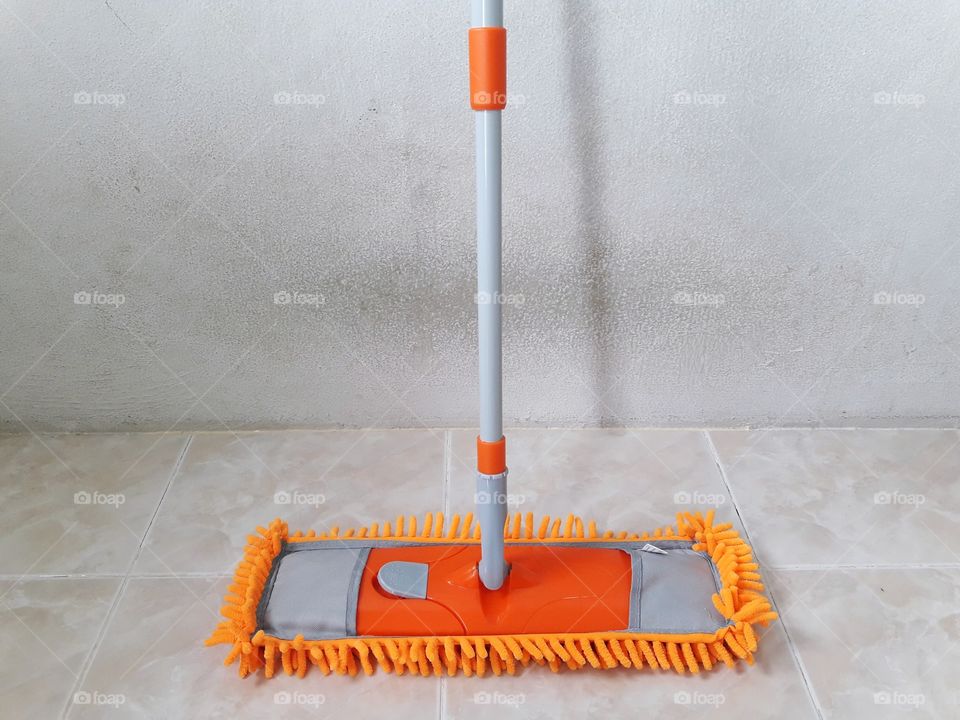 orange mop on floor with dirty wall
