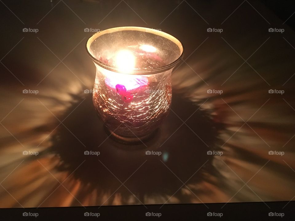 Stained glass candle holder spreading the light of the candle in a pattern all around it, multiplying the light’s effect 