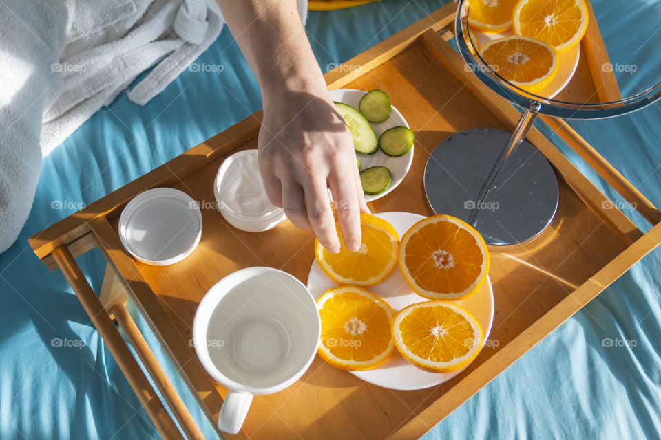 A man at home takes care of himself and does a manicure at home on a blue background and with orange.