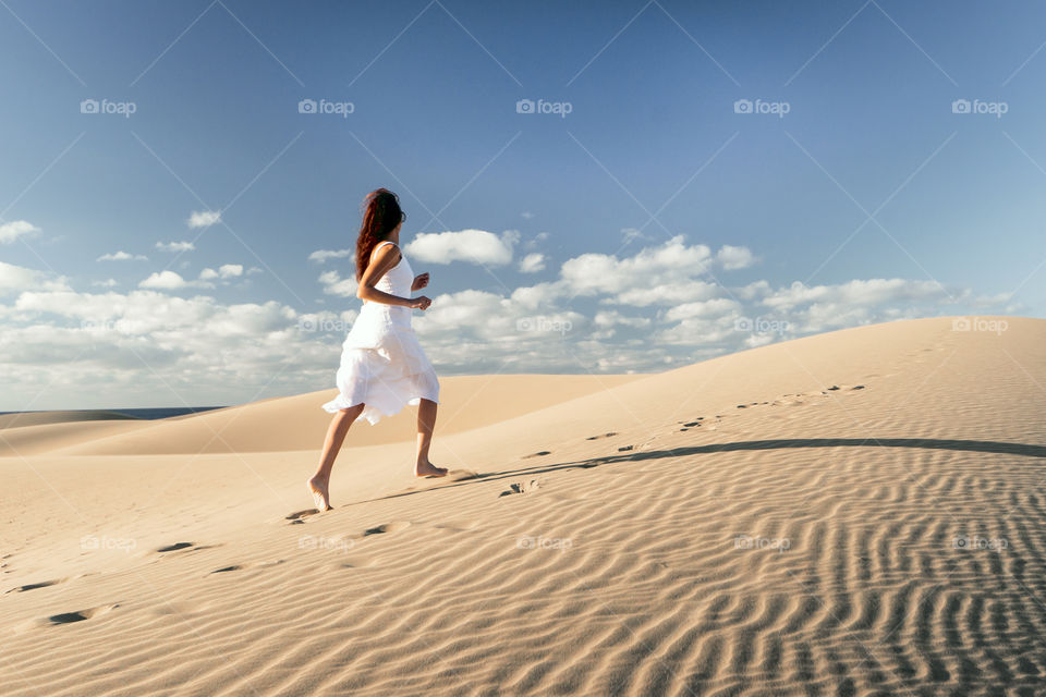 Girl running in desert dune