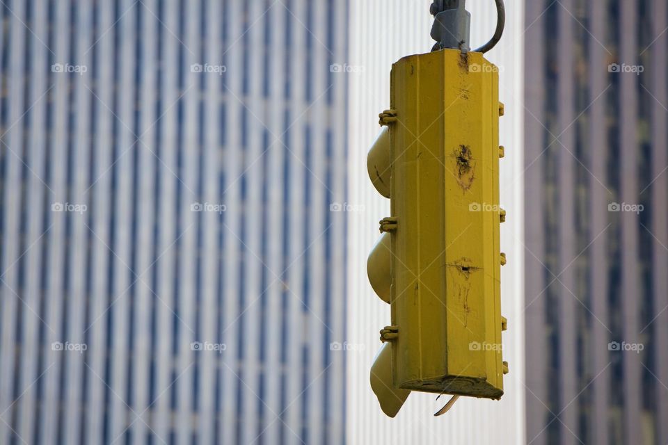 A Manhattan , New York City, yellow traffic light  with blurred background office buildings.