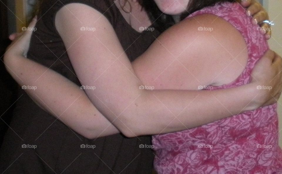 close up view of two young women's arms hugging in sisterly friendship