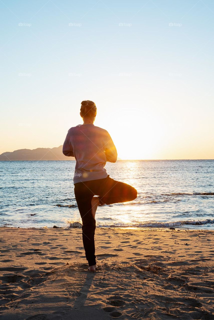 woman doing yoga on beach