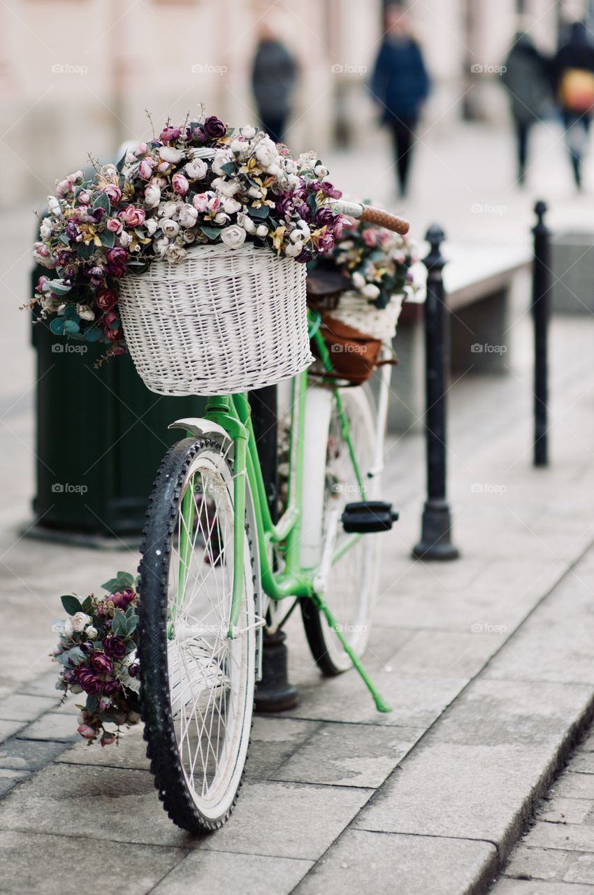 beautiful retro bicycle with a basket of flowers parked in the city and waiting for the owner