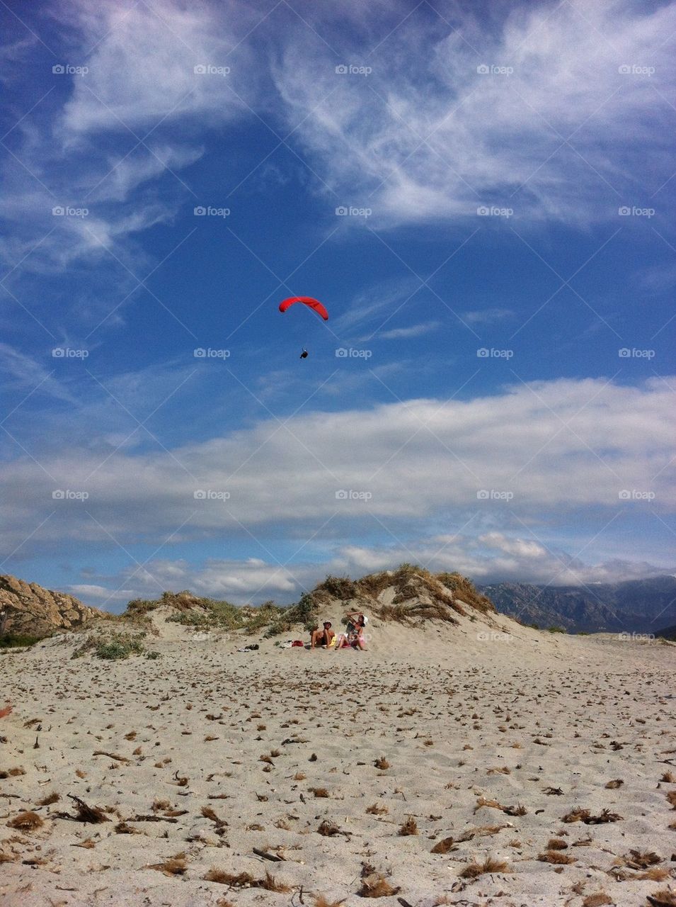 Couple on the beach looking up at paraglider