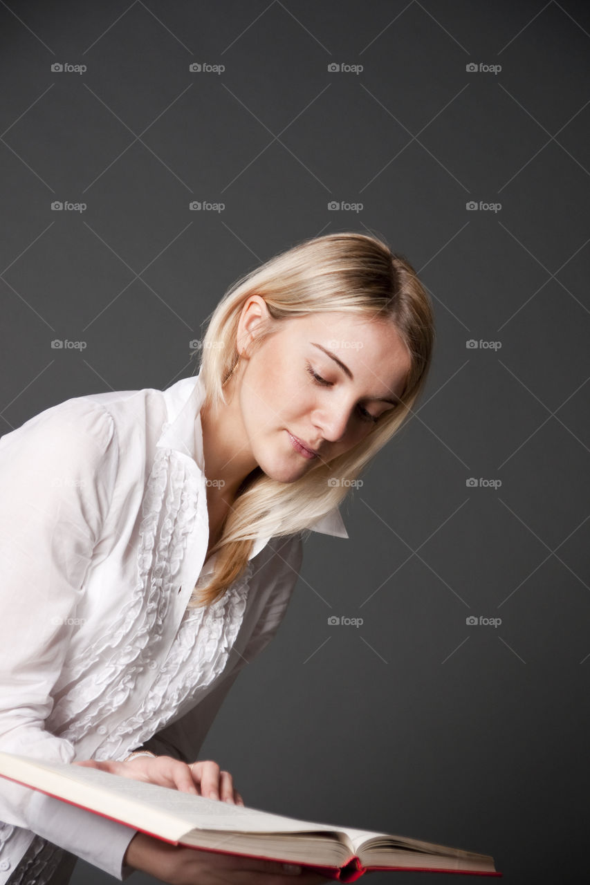 The student girl reads the book. Studio, on a grey background.