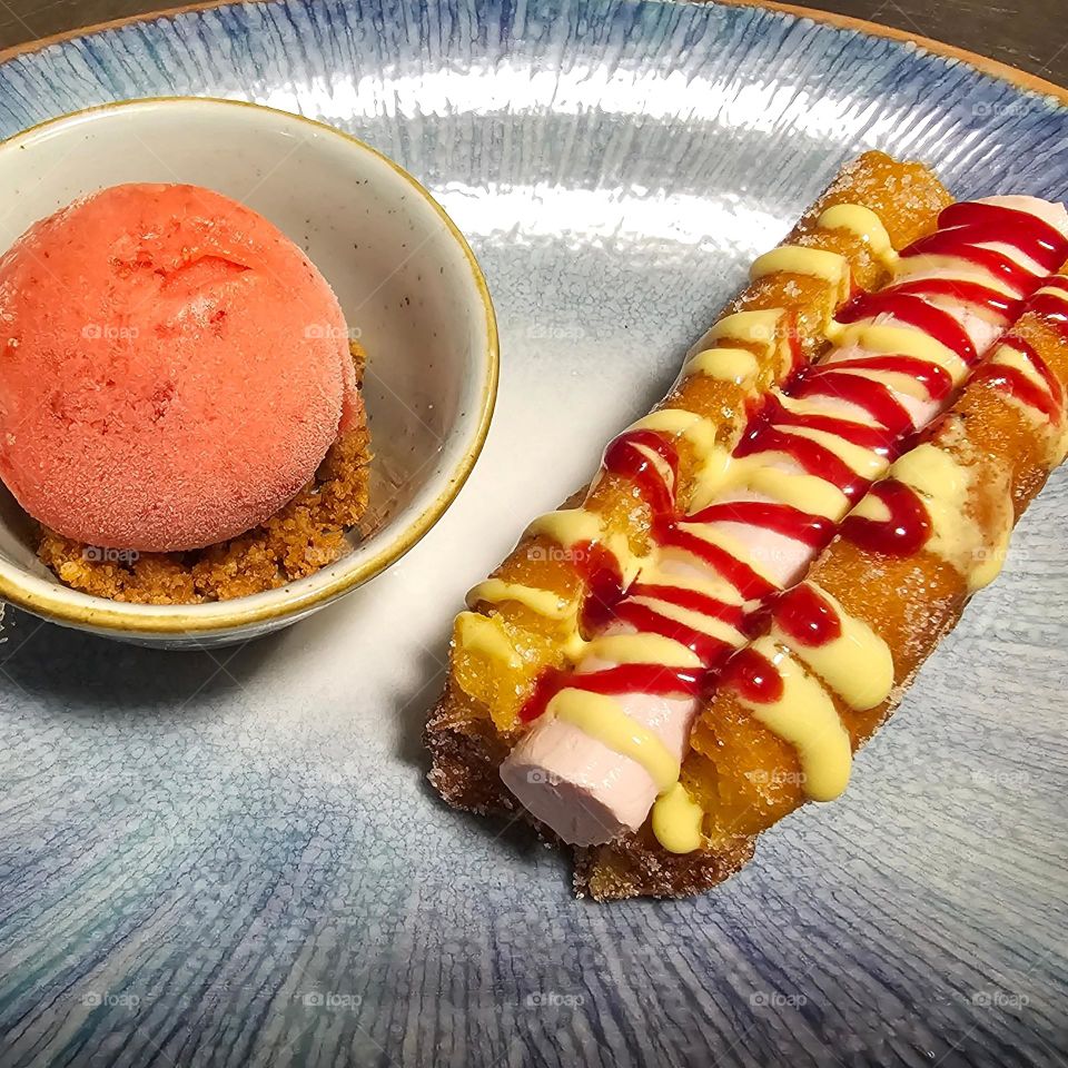 Este postre esta inspirado en un frankfurt= hot dog es una torrija con helado de frutos rojos lo que seria el ketchup es coulis de frutos rojos y lo que seria la mostaza es coulis de mango y para refrescar un poco helado de fresa