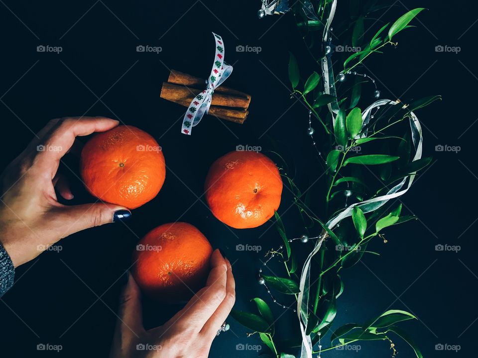 A human hand holding orange against black background