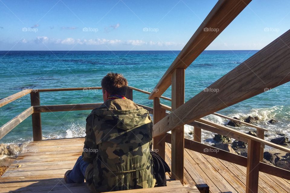 Man sitting on stairs by the sea