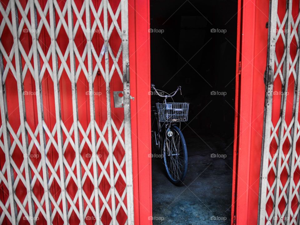 A lonely bicycle parked inside a shop with steel doors in Melaka, Malaysia