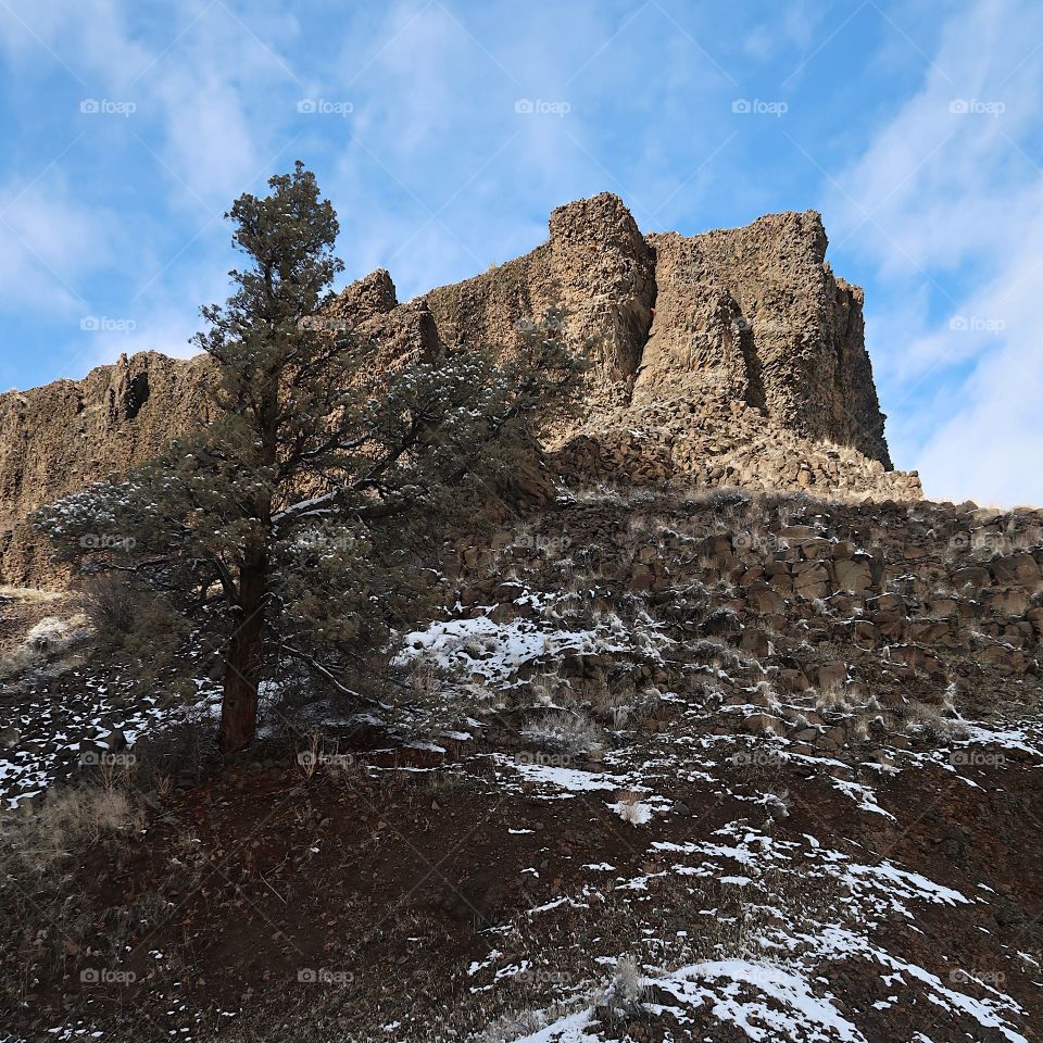 Cliffs of basalt stick out with just a bit of snow on the ground on a beautiful sunny winter day in Central Oregon. 