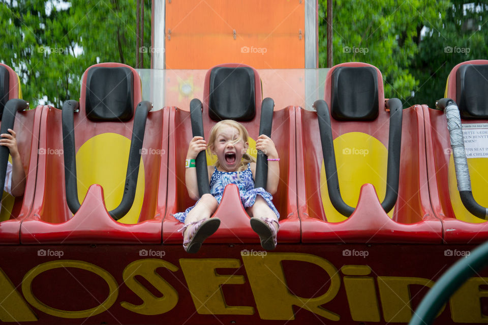 Young girl six years old riding a carousel at the amusement park Bakken in Denmark.