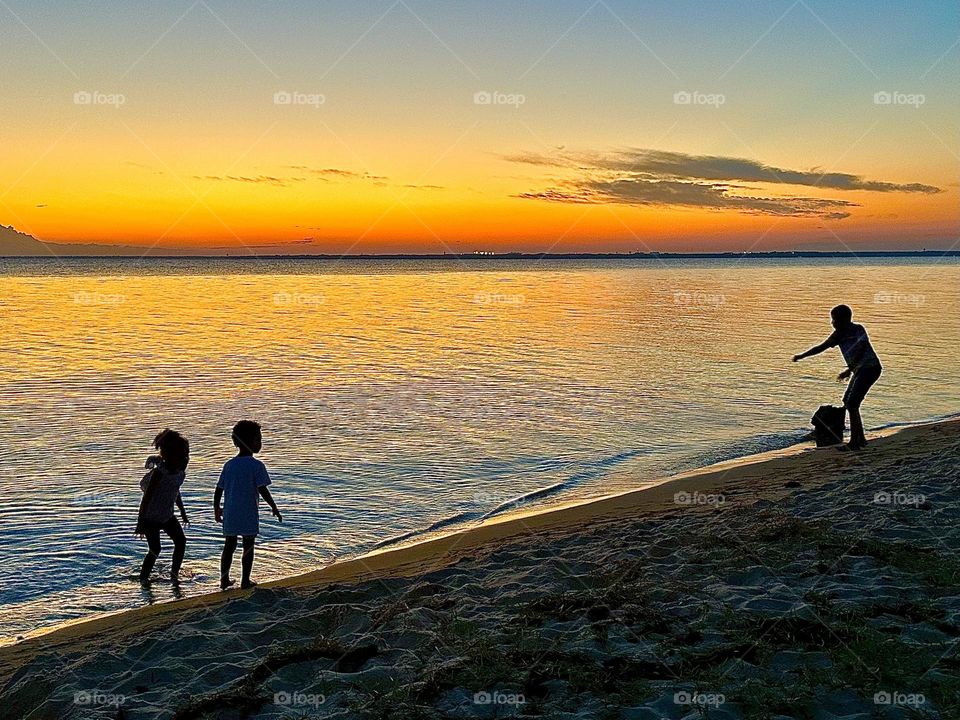 Beach sunset - A father, son and daughter playing on the sandy beach of the Gulf of Mexico during a magnificent and colorful sunset