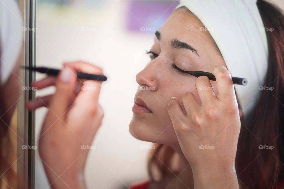 Young woman is putting on an eye liner