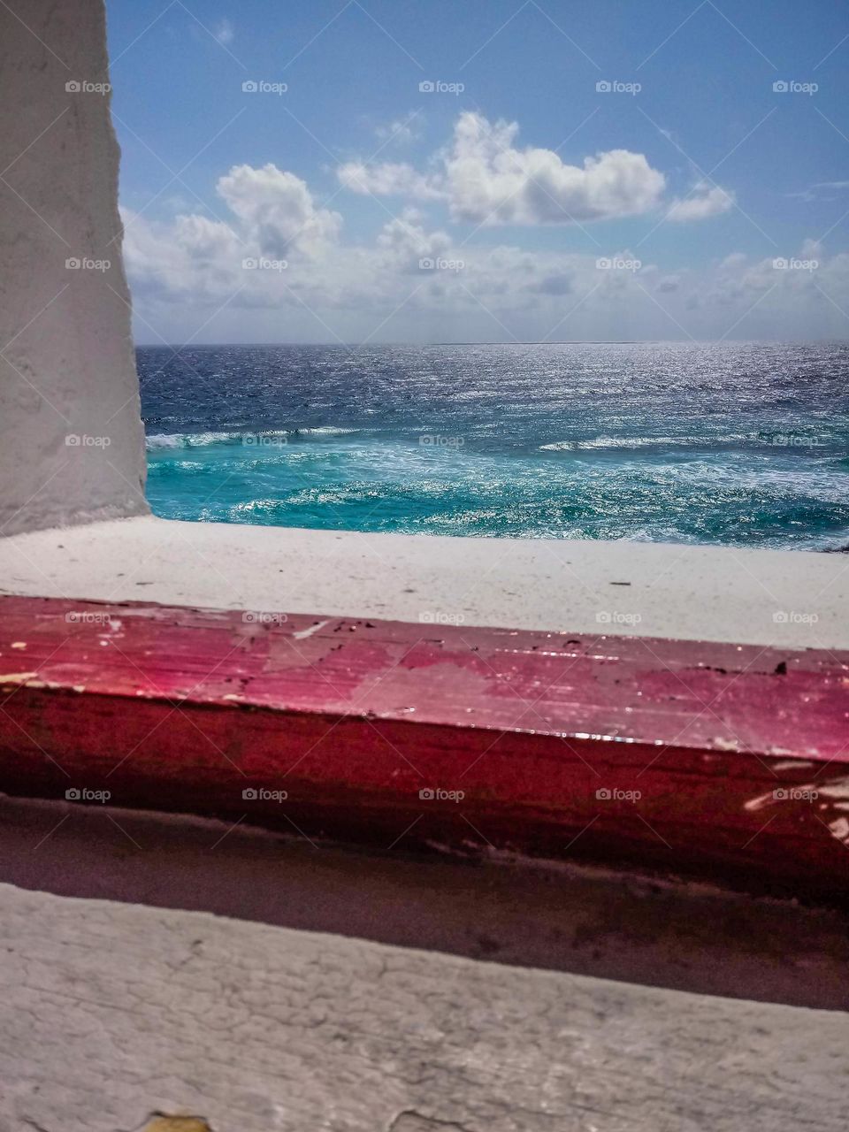 Light house window red window frame snap shot of the deep blue ocean water with rolling clouds