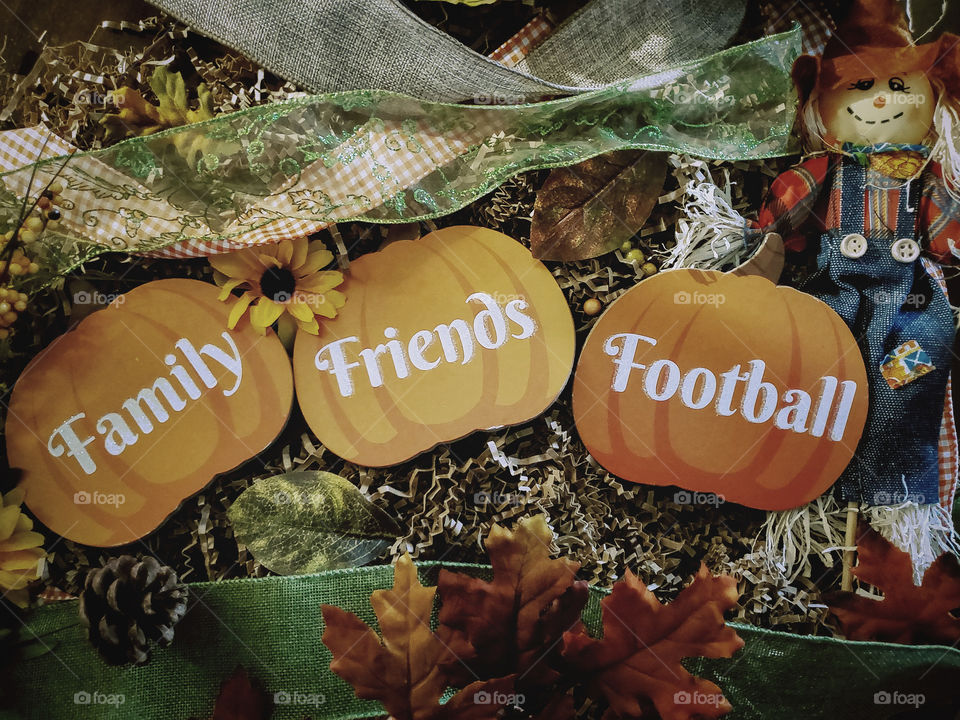 November celebrations flat lay - Family,  friends and Football pumpkins, fall leaves, fall ribbons and a scarecrow.