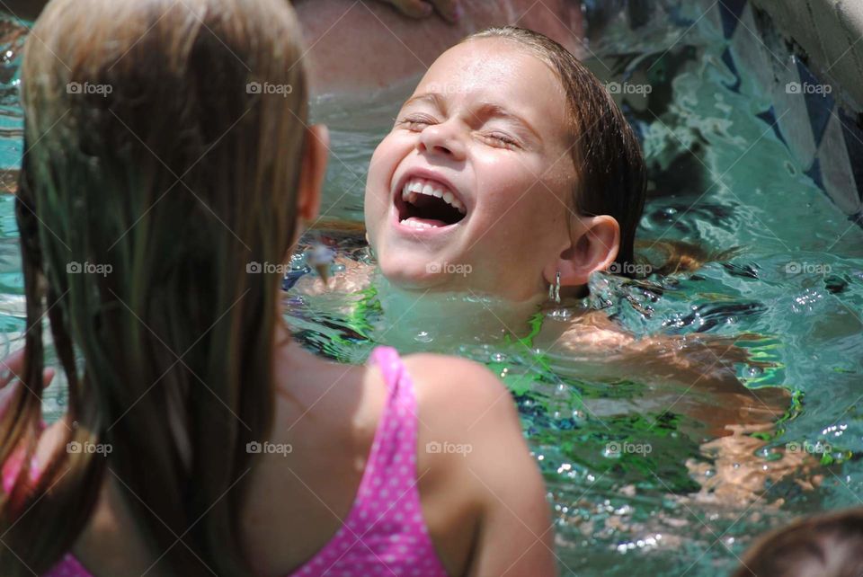 summer fun image of a young girl's face laughing and enjoying the pool with friends
