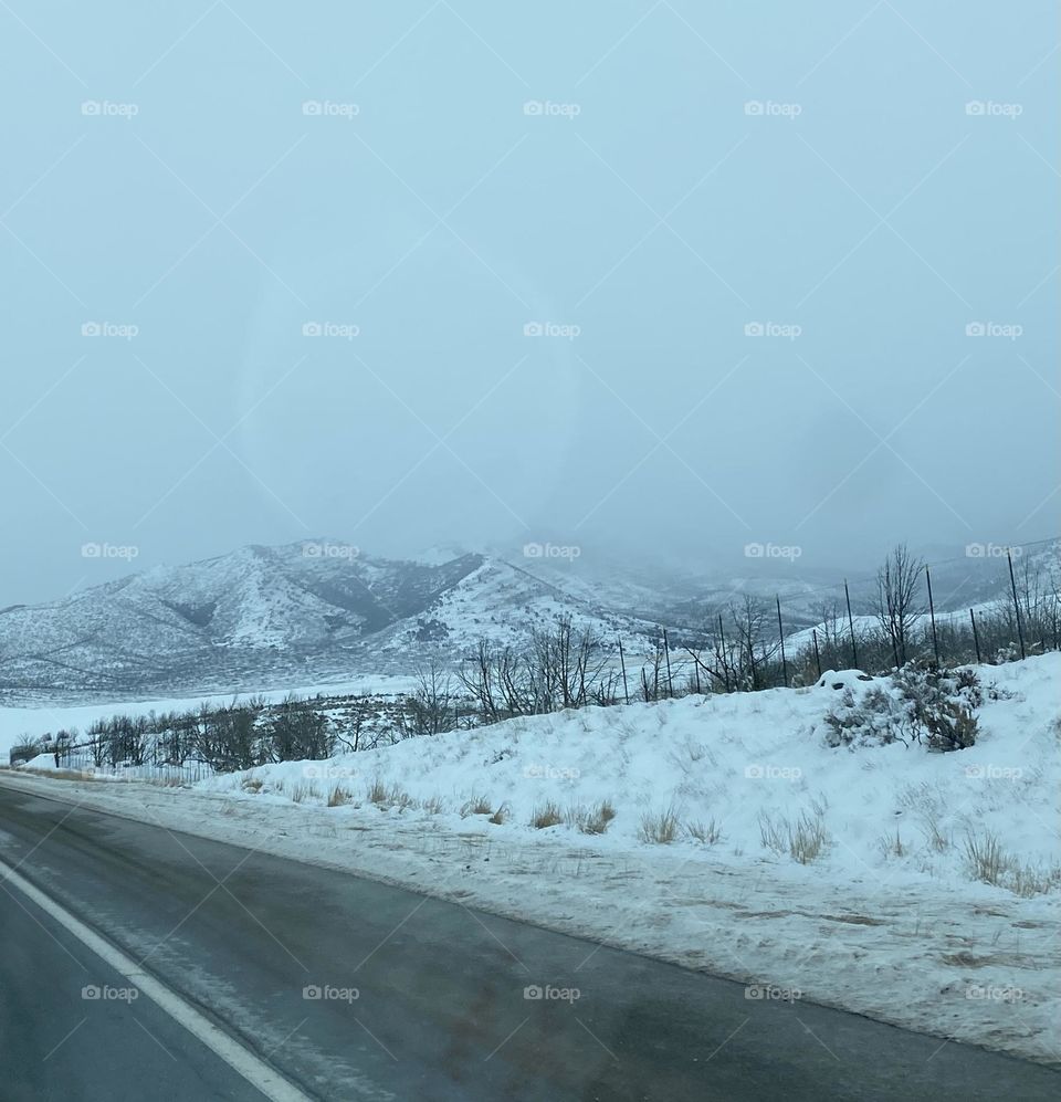 Snow on a mountain and on the ground around a road. 