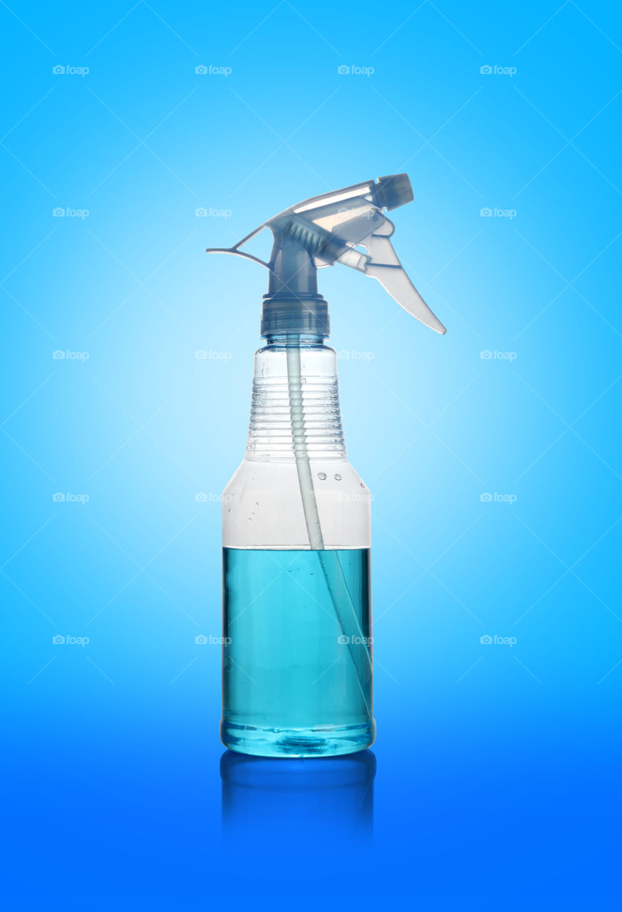 Transparent spray water cleaner bottle on blue background