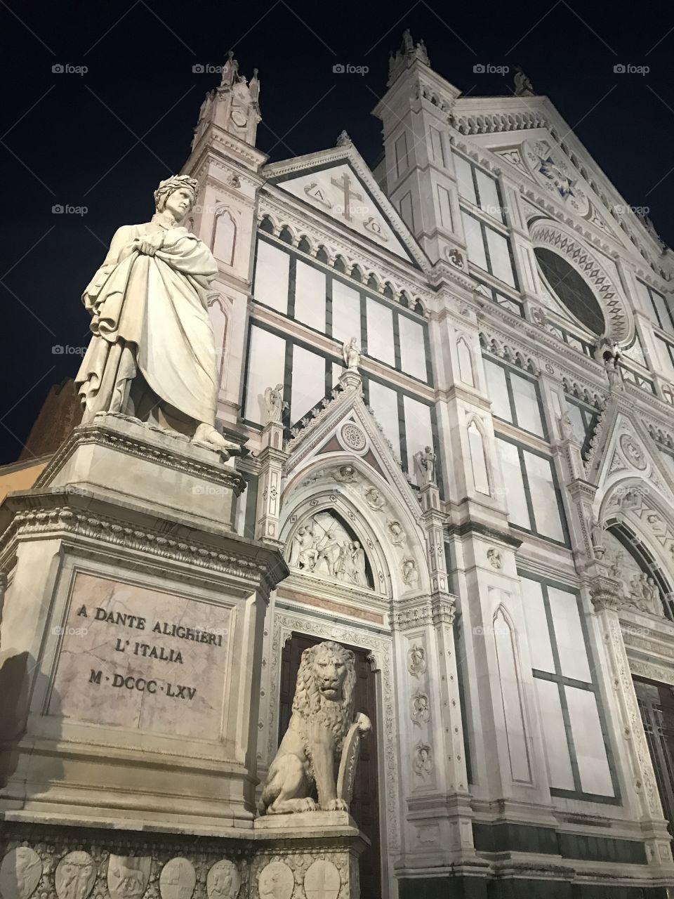 Dante Alighieri statue outside Santa Croce in Florence, Italy in the dark night.