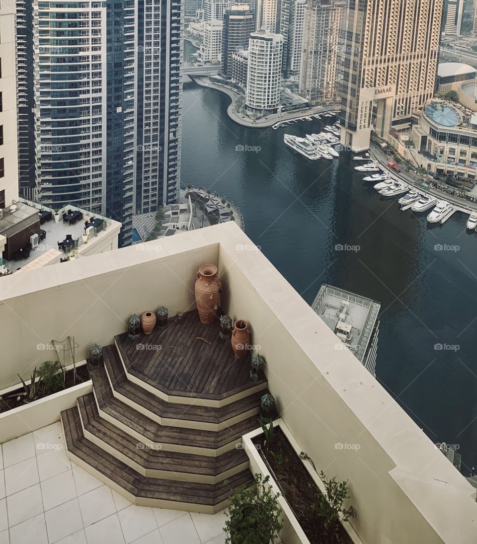 Beautiful skyscrapers view with water between, vessels and wooden terrace at high floor 