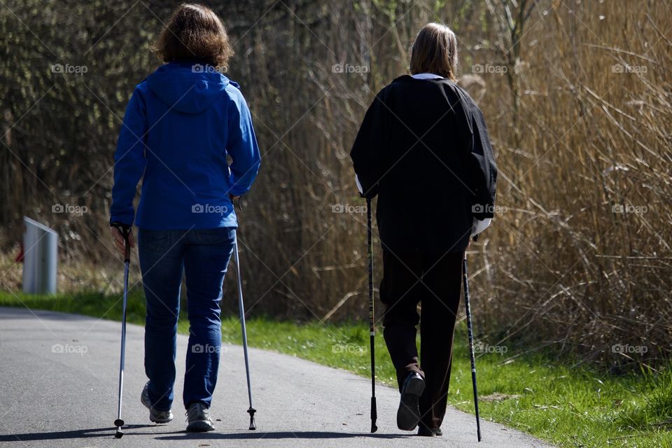 Two people walking with hiking pole on country road