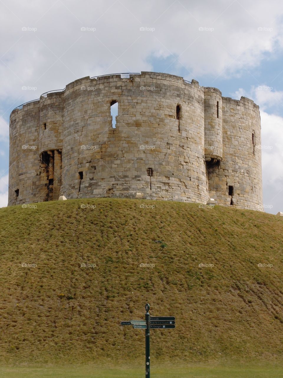 Clifford’s Tower, a local stone landmark in York in England, sits majestically on top of a hill on a sunny day. 