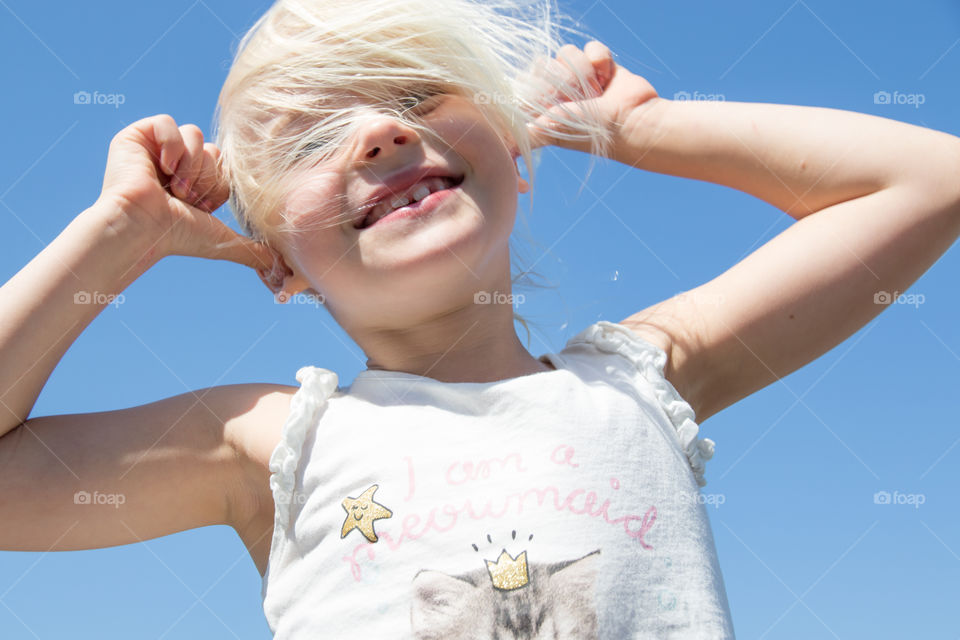 Young happy little girl with a big smile, on a beautiful summer day with blue sky 
