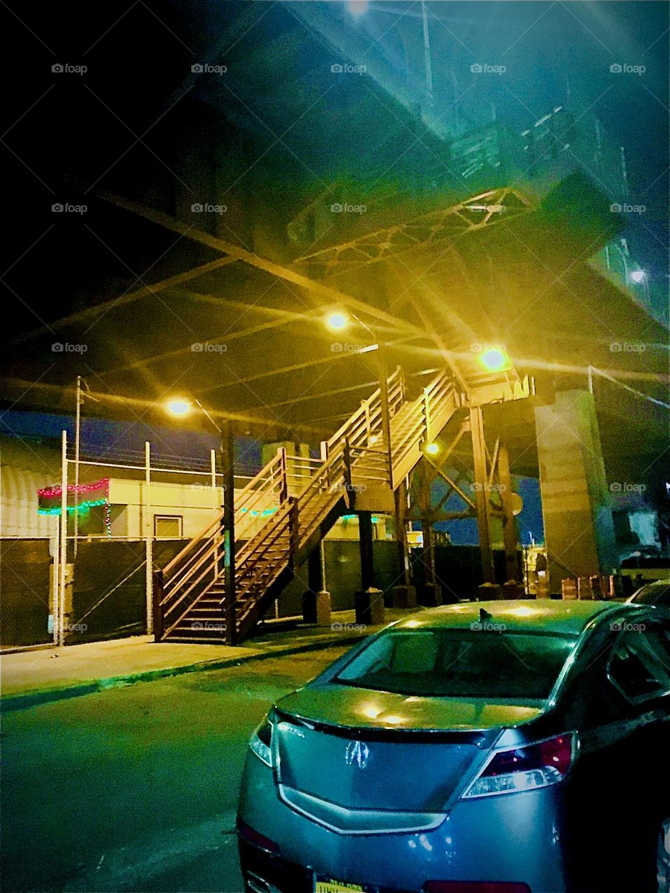 These multiple spotlights are illuminating the way up the stairs to the pedestrian lane of the „Pulaski Bridge“ at „Newtown Creek“ in LIC, Queens. This is how to get across the bridge on foot into „Greenpoint“, Bklyn. 2021. Hypnotic Productions