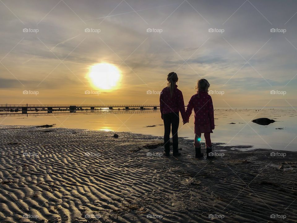 Children holding hands in sunset