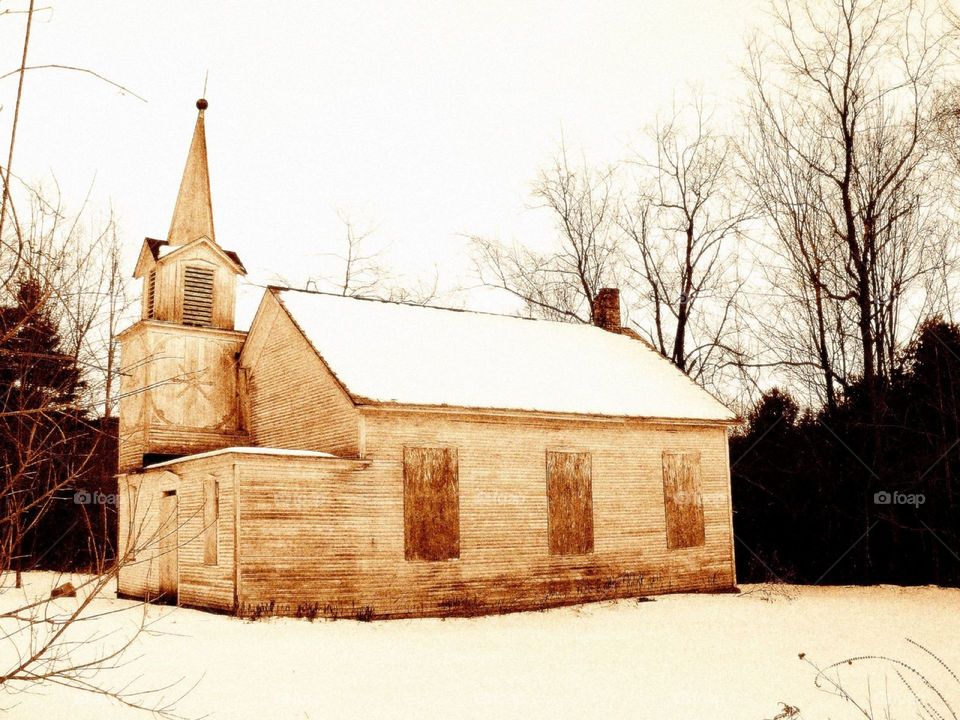 Forgotten winter chapel . A lone abandoned wooden chapel,  sits silently in the snowy countryside