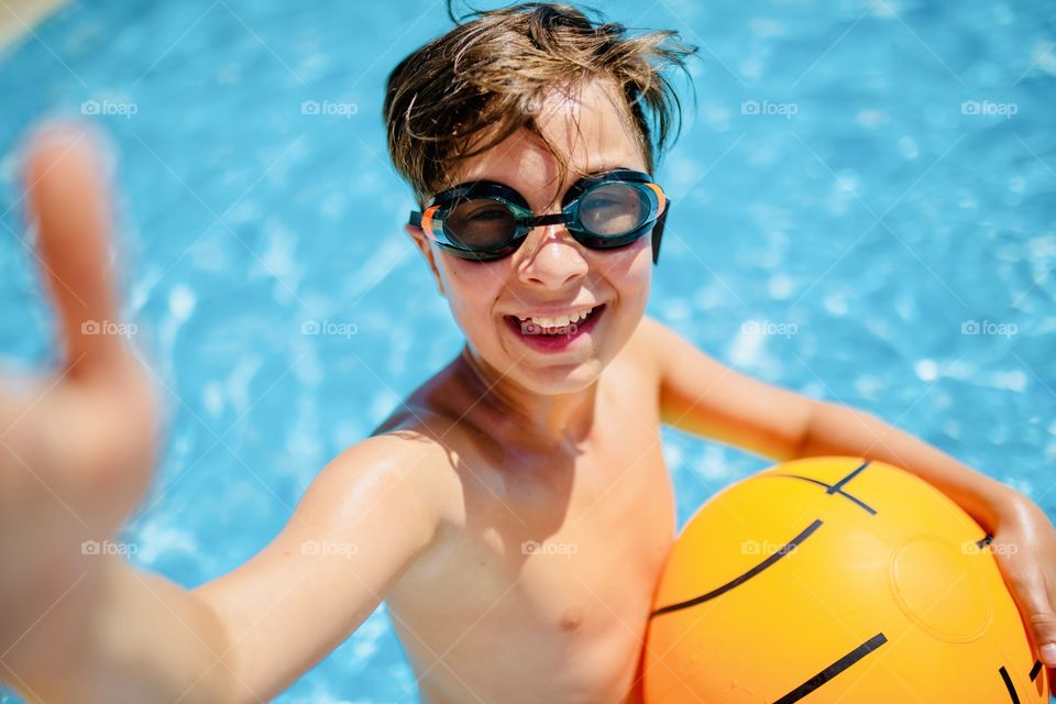boy makes funny selfie in the pool